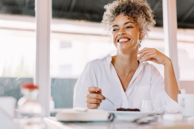 Cheerful woman having lunch alone in a cafe.